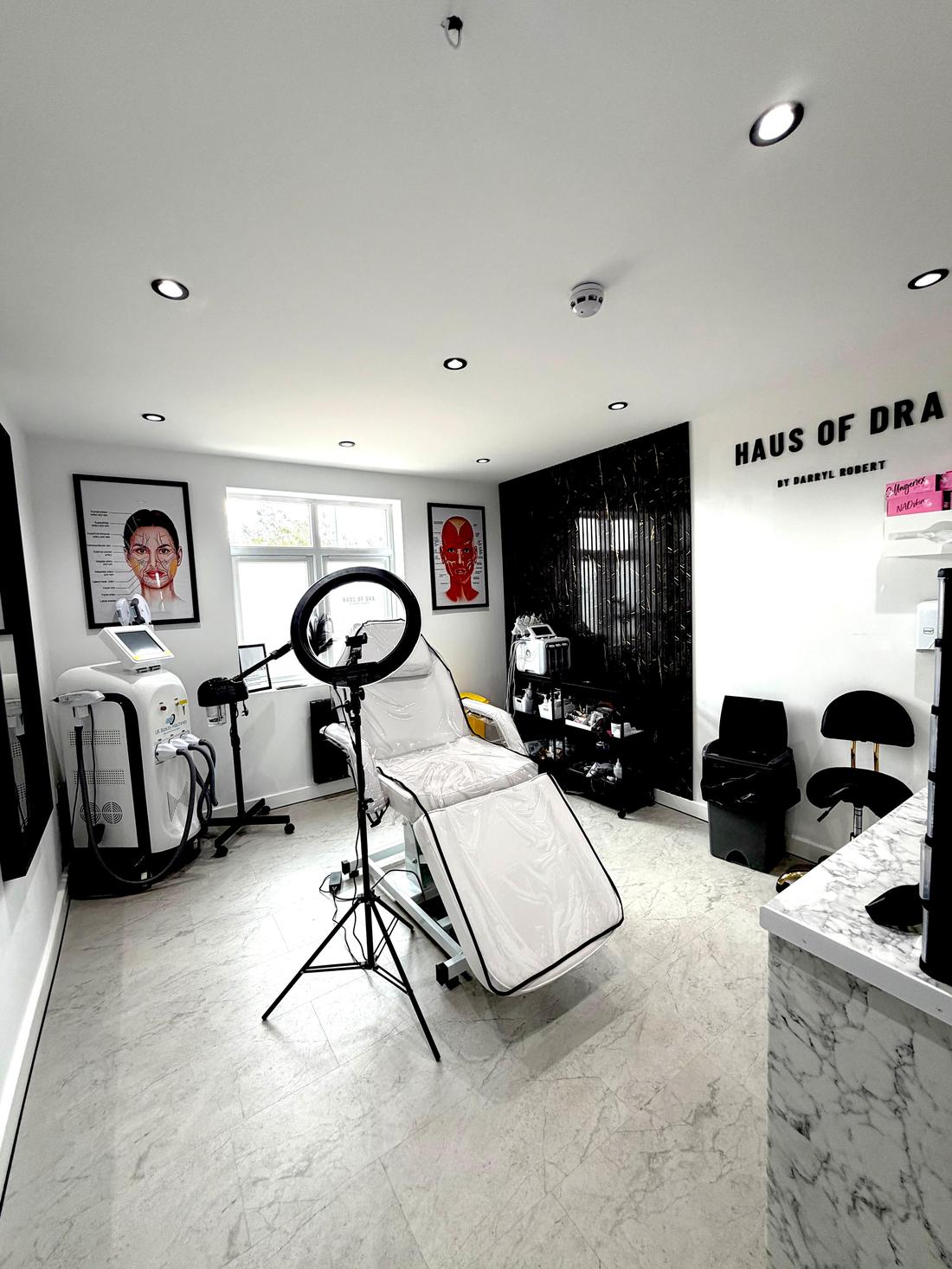 A second treatment room at HAUS of DRA, with laser and skin equipment and anatomy charts on the wall.