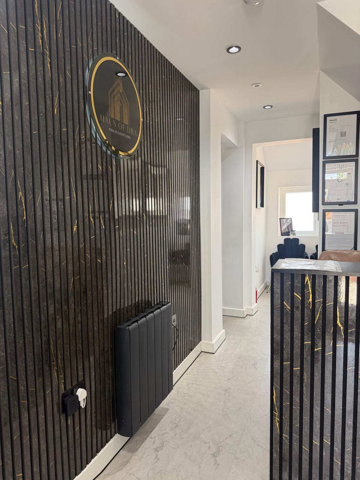 The entrance hallway at HAUS of DRA, with the gold house emblem on dark fluted marble panelling.